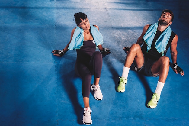 Foto gratuita pareja cansada en el suelo de gimnasio