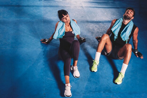 Pareja cansada en el suelo de gimnasio