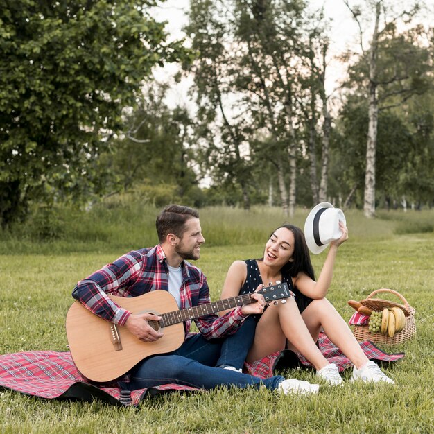 Pareja cantando sobre manta de picnic