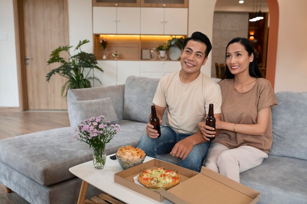 Pareja cariñosa en casa con pizza y cerveza