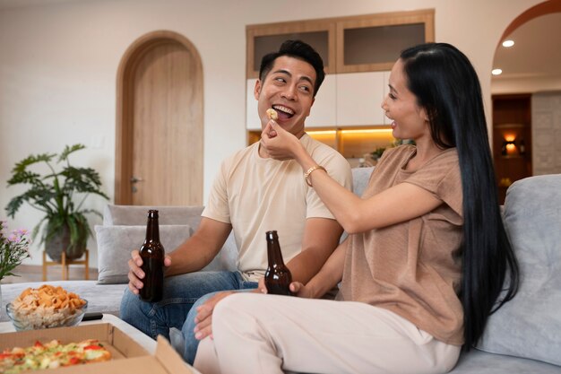 Pareja cariñosa en casa con pizza y cerveza