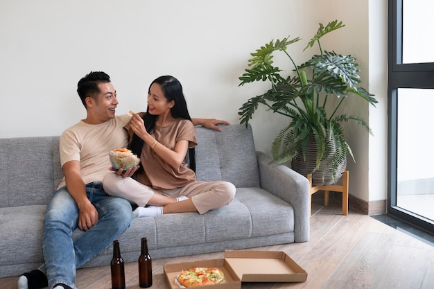 Pareja cariñosa en casa con pizza y cerveza