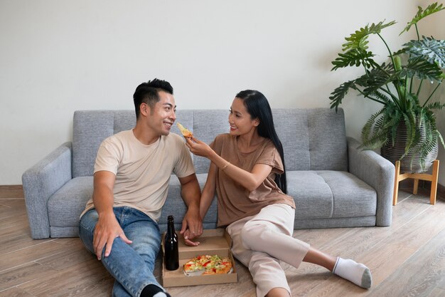 Pareja cariñosa en casa con pizza y cerveza