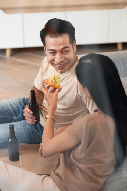 Pareja cariñosa en casa con pizza y cerveza