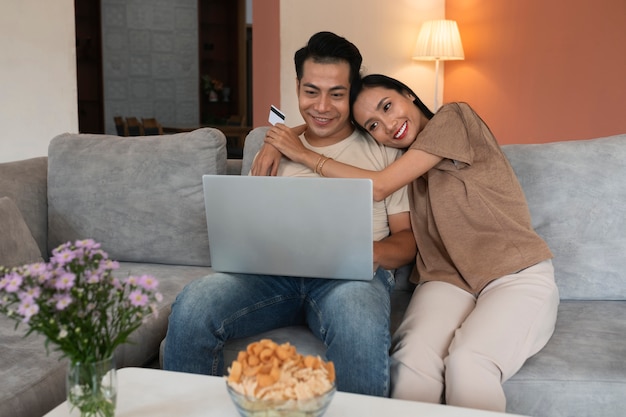 Una pareja cariñosa en casa trabajando en una laptop mientras se sienta en el sofá