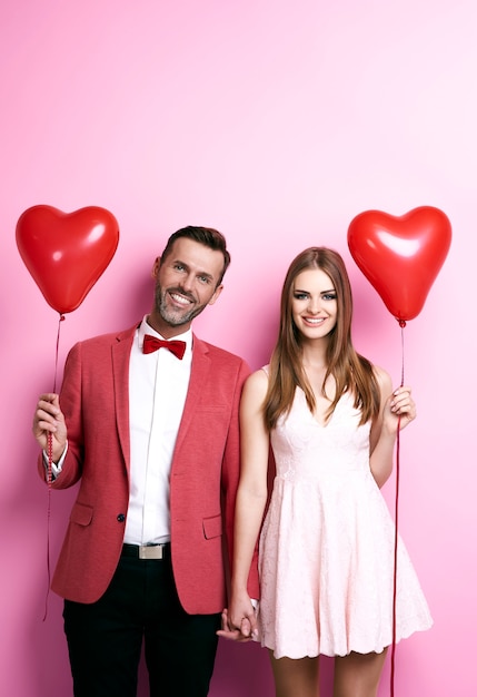 Pareja cariñosa con globos en forma de corazón tomados de la mano