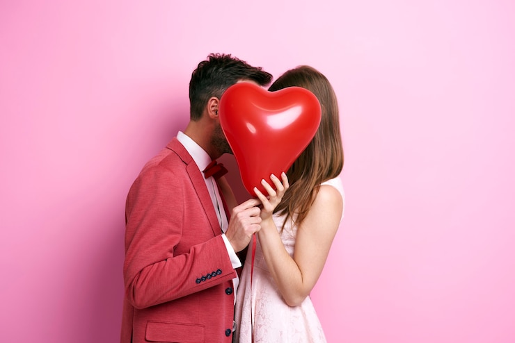 Foto gratuito pareja cariñosa que cubre la cara con globo y besos