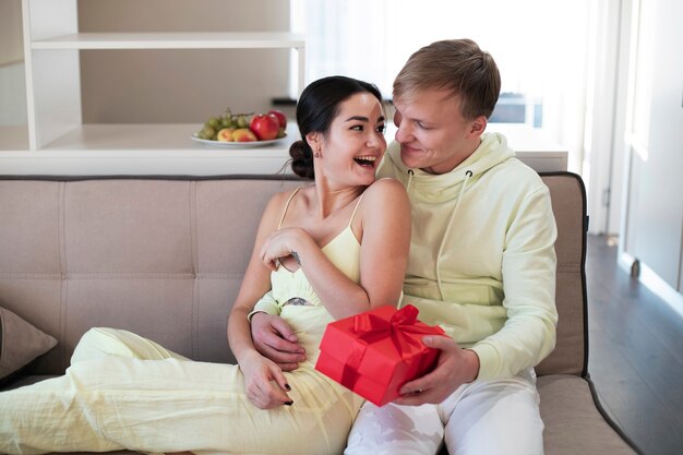 Pareja en casa celebrando el día de San Valentín con caja de regalo