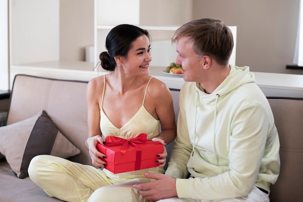 Pareja en casa celebrando el día de San Valentín con caja de regalo