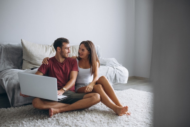 Pareja en casa junto sentado en el piso con computadora