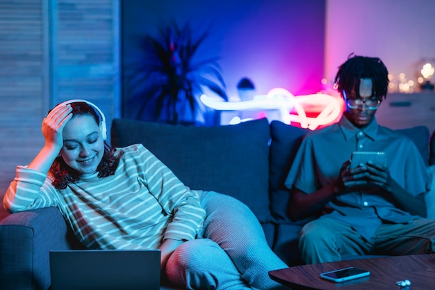 Pareja en casa juntos en el sofá con dispositivos modernos