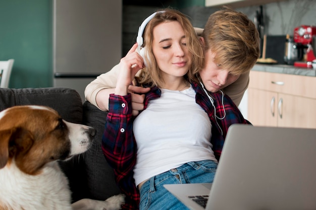 Pareja en casa con perro usando laptop