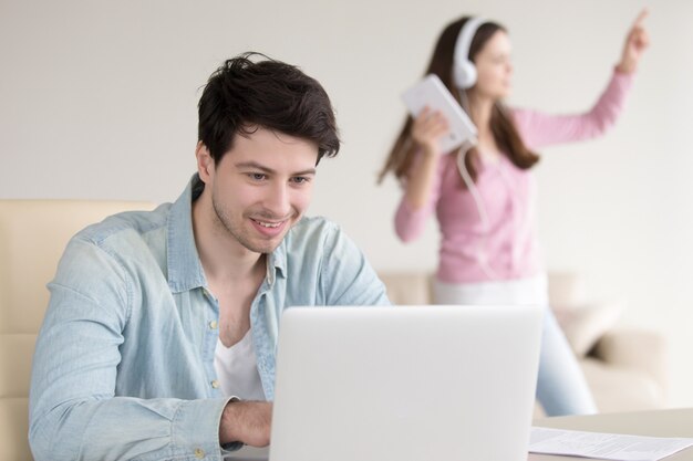 Pareja en casa usando laptop y tablet, trabajo y entretenimiento