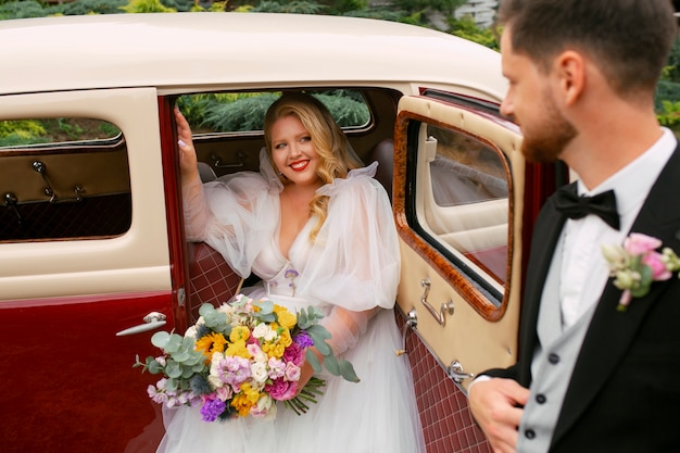 Foto gratuita pareja casada de tiro medio posando con autos antiguos