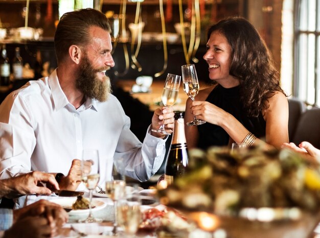 Pareja caucásica tintinear vasos juntos en el restaurante