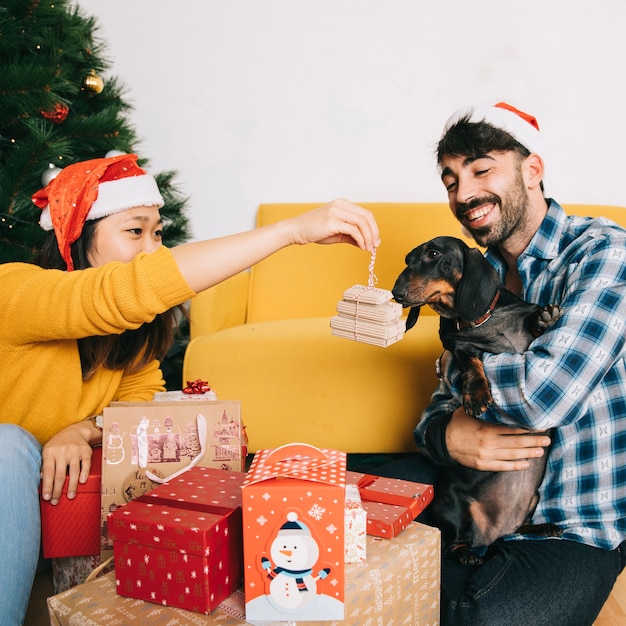 Foto gratuita pareja celebrando navidad con perro y regalos