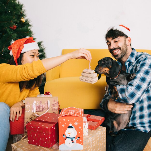 Pareja celebrando navidad con perro y regalos