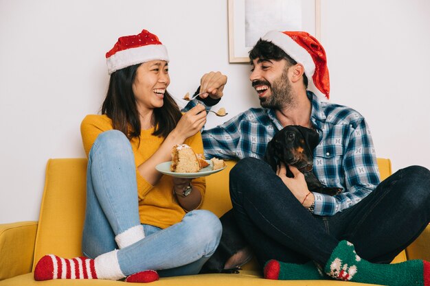 Pareja celebrando navidad en sofá con perro