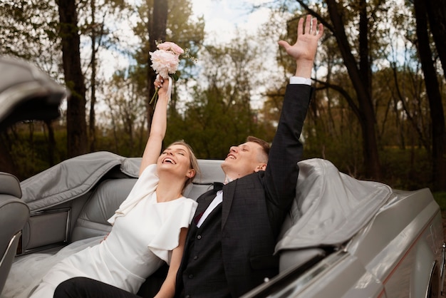 Pareja celebrando en su coche de recién casados