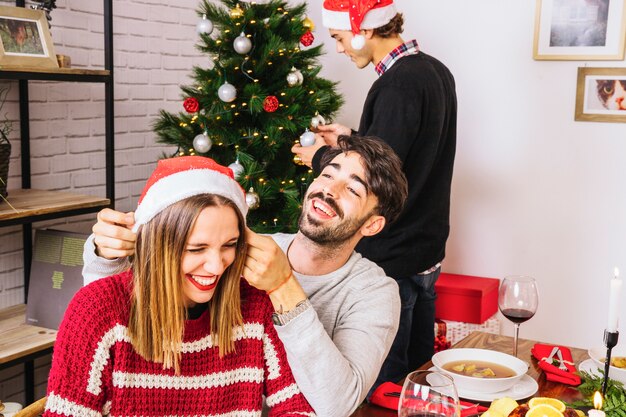 Pareja en cena de navidad y hombre en el fondo