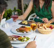 Foto gratuita pareja cenando con filete de salmón ahumado, pescado a la parrilla, filete de cordero y vino