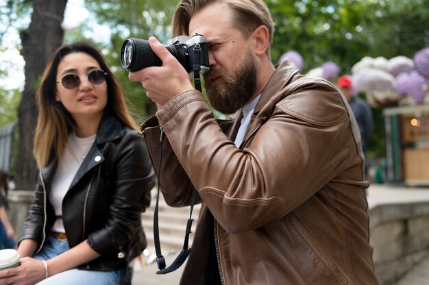 Pareja en chaquetas de cuero sintético con cámara de fotografía al aire libre