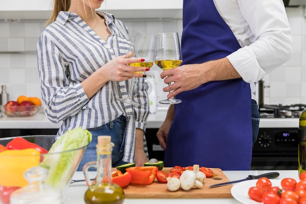 Pareja chocando copas de vino en la cocina