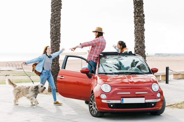 Pareja en coche saludo mujer con perro al aire libre