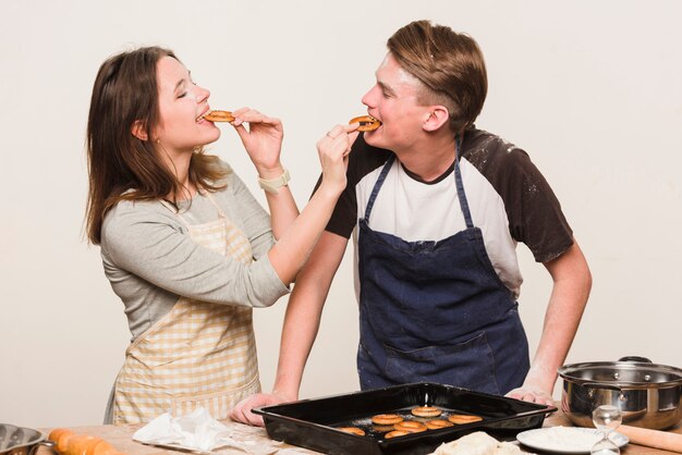 Pareja cocinando juntos y degustando pasteles.