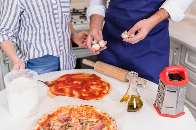 Pareja cocinando pizza con champiñones