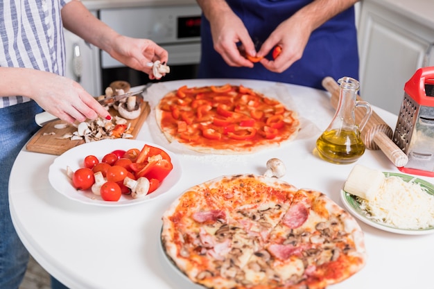 Pareja cocinando pizza con verduras y setas