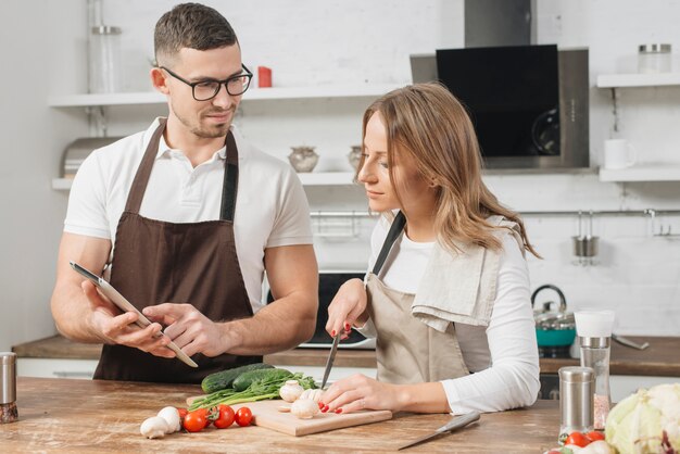 Pareja cocinando con tableta en casa