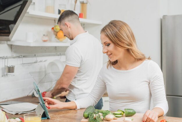 Pareja cocinando con tableta en casa