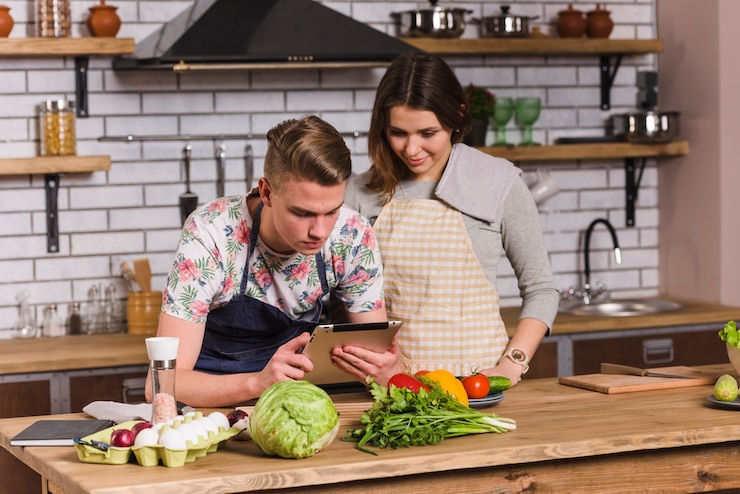 Foto gratuito pareja cocinando y usando tableta en la cocina