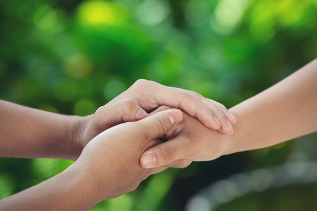 Foto gratuita pareja cogidos de la mano en el prado verde.