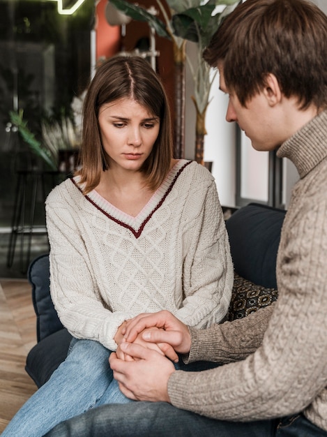 Pareja cogidos de la mano en el sofá