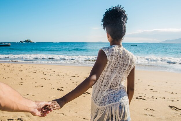 Pareja cogiéndose las manos en la playa vista trasera