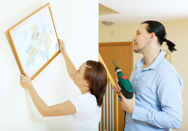 Pareja de colgar el cuadro de arte en la pared