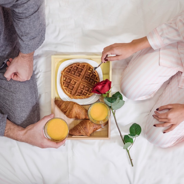 Foto gratuita pareja comiendo desayuno romántico en la cama