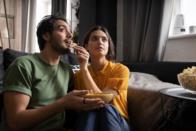 Foto gratuita pareja comiendo juntos en casa en el sofá