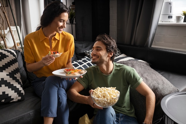 Pareja comiendo juntos en casa en el sofá