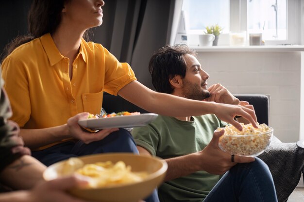 Pareja comiendo juntos en casa en el sofá