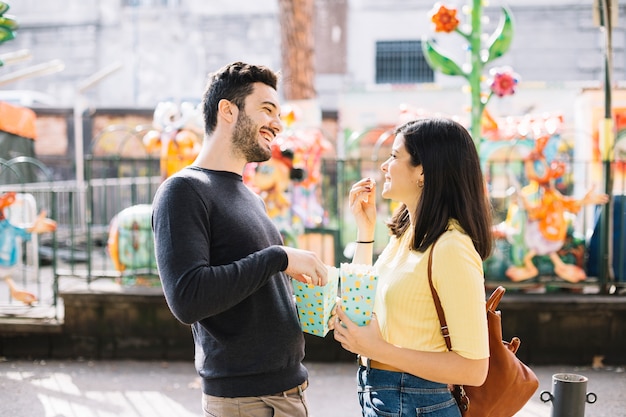 Pareja comiendo palomitas en el parque de atracciones