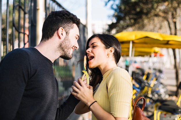 Pareja comiendo piruleta en el parque de atracciones