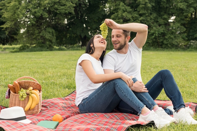 Pareja comiendo uvas en manta de picnic