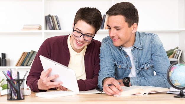 Foto gratuita pareja de compañeros de clase que miran la tableta