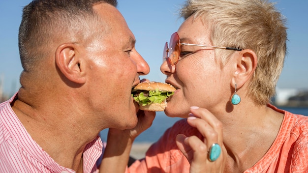 Pareja compartiendo una hamburguesa al aire libre