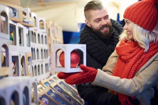 Pareja comprando la bola navideña más grande en el mercado navideño