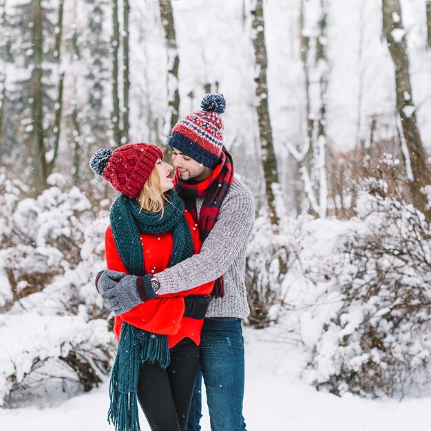 Pareja de contenido relajado abrazando en la nieve