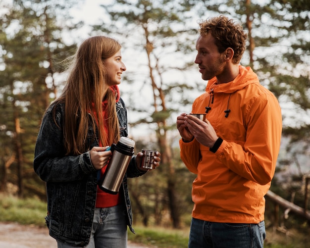 Foto gratuita pareja conversando sobre una bebida caliente durante un viaje por carretera